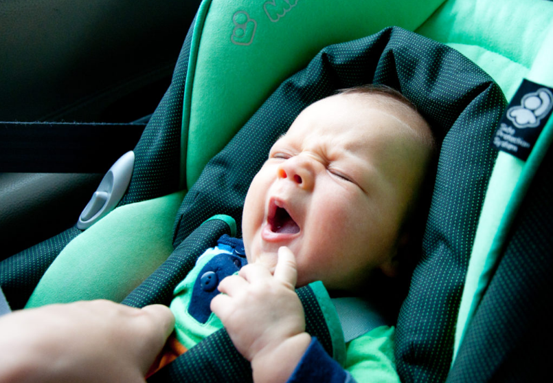 Baby yawning in a car seat