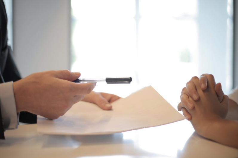 Hands of two people with a document and a pen